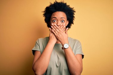 Gayri resmi tişört giyen kıvırcık saçlı, Afro-Amerikan bir kadın ağzını yanlışlıkla ellerle kapatmış. Gizli konsept.