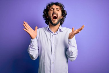Mor arka plan üzerinde duran sakallı genç ve yakışıklı iş adamı kollarını kaldırmış ve gözleri kapalı heyecanla haykırarak başarının çılgınlığını kutluyor. Kazanan konsept