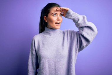 Mavi gözlü genç bir kadın pembe arka planda balıkçı yaka kazak giyiyor. Çok mutlu ve gülümsüyor. Konsept aranıyor.