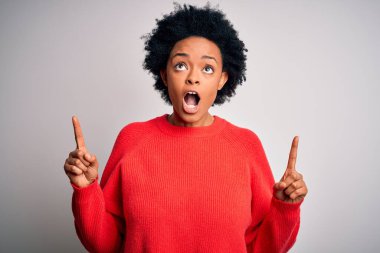 Kıvırcık saçlı, kırmızı süveter giyen güzel Afro-Amerikan kadın şaşırmış ve şaşırmış bir şekilde yukarı bakıp parmaklarını göstermiş ve kollarını kaldırmıştı..