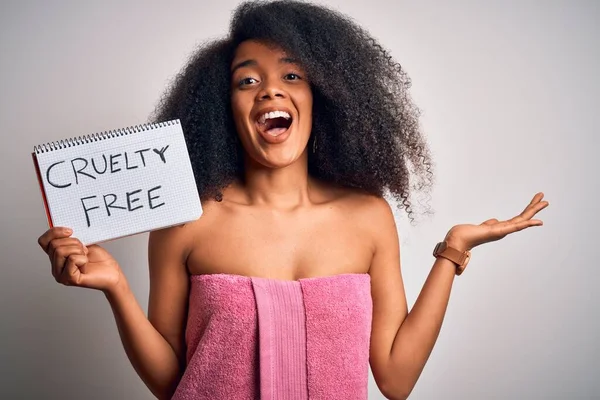 Young african american woman with afro hair wearing a towel asking for cruelty free beauty very happy and excited, winner expression celebrating victory screaming with big smile and raised hands