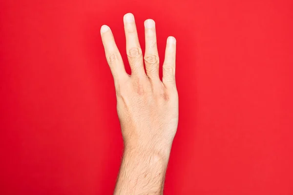 stock image Hand of caucasian young man showing fingers over isolated red background counting number 4 showing four fingers