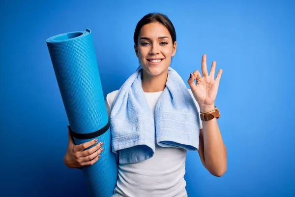 年轻美丽的黑发女运动员穿着毛巾 拿着垫子做瑜伽 手握手签 很好的象征 — 图库照片