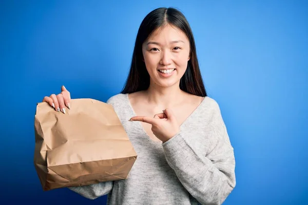 파란색외진 음식을 배달용 가방을 아시아 여인은 손가락으로 행복하게 가리켰다 — 스톡 사진