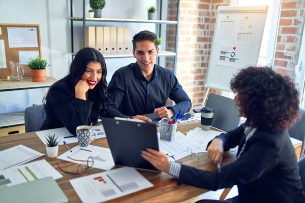 Group of business workers smiling happy and confident. Working together with smile on face reading documents and  speaking at the office