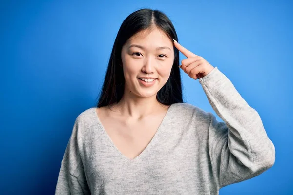 Młoda Piękna Azjatycka Kobieta Ubrana Luźny Sweter Stojąca Nad Niebieskim — Zdjęcie stockowe