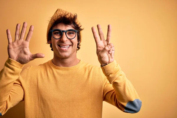若いですハンサムな男身に着けていますカジュアルTシャツと眼鏡上の隔離された黄色の背景表示し 指番号8で指摘しながら 自信と幸せ — ストック写真