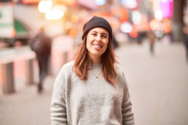 Mutlu ve kendinden emin gülümseyen genç ve güzel bir kadın. Yüzünde gülümsemeyle kentte yürürken