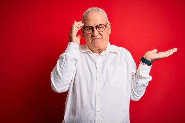 Orta yaşlı, beyaz gömlekli, kırmızı arka planda gözlüklü, açık avuç içiyle fotokopi çeken ve alnını işaret eden yakışıklı bir adam. Bunu bir düşün..