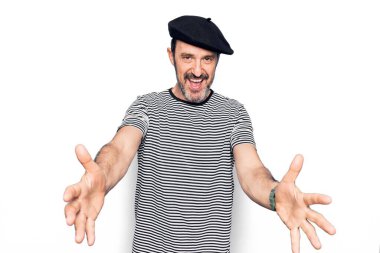 Beyaz arka planda çizgili tişört ve Fransız beresi giyen orta yaşlı yakışıklı bir adam kucaklanmak için kollarını açıp kameraya bakıp gülümsüyor. Mutluluğu kucaklayan neşeli bir ifade..