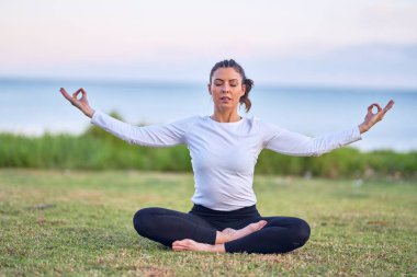 Genç yakışıklı sporcu yoga yapıyor. Koç parkta lotus poz öğretiyor.