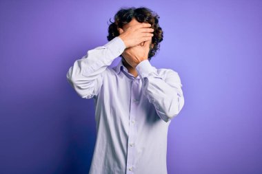 Mor arka plan üzerinde duran sakallı yakışıklı iş adamı gözleri ve ağzı kapalı, şaşırmış ve şok olmuş. Duygularını gizliyor.