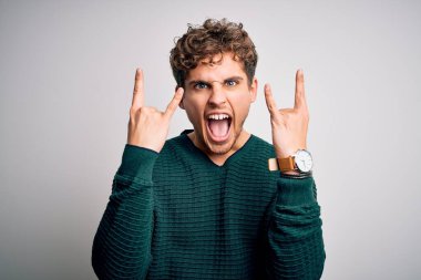 Sarışın, kıvırcık saçlı, beyaz arka planda yeşil kazak giyen çılgın bir ifadeyle elleri havada rock sembolü yapan genç bir adam. Müzik yıldızı. Ağır konsept.