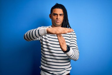 Rastgele çizgili süveter giyen Afro saçlı genç, yakışıklı Afro adam. Elleriyle, hayal kırıklığına uğramış ve ciddi bir yüz ifadesiyle mola veriyor.