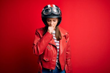 Motosiklet kaskı takan, kırmızı ceketli, kendini kötü hisseden ve soğuk algınlığı veya bronşitin belirtisi olarak öksüren güzel, esmer bir kadın. Sağlık hizmeti kavramı.