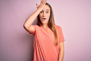 İzole edilmiş pembe arka planda duran sıradan tişörtler giyen genç ve güzel bir kadın. Yanlışlıkla el ele tutuşarak şaşırmış. Hatayı hatırla. Unuttum, kötü hafıza konsepti.