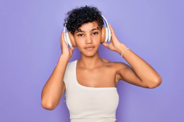 Güzel afro-amerikan kadın müzik dinliyor kırmızı arka planda kulaklık takıyor ve akıllı yüzünde kendine güvenen bir ifade var.