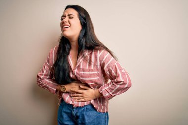Genç esmer kadın, izole edilmiş arka planda, mide bulantısı ve acı veren hastalıklardan dolayı günlük çizgili gömlek giyiyor. Ache kavramı.
