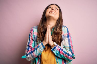Genç, güzel, esmer, sıradan bir gömlek giyen, pembe arka planda duran, elleri bağlı yalvaran ve dua eden bir kadın. Yüzünde umut ifadesi olan çok duygusal ve endişeli bir ifade. Yalvarıyorum..