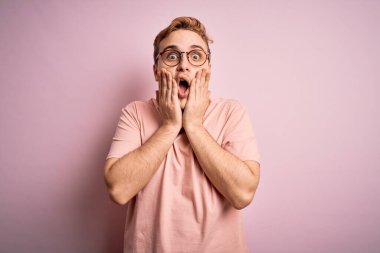 Genç, yakışıklı, sıradan tişörtlü bir adam pembe arka planda dikiliyor. Korkmuş ve şok olmuş. Şaşırmış ve şaşırmış bir halde.