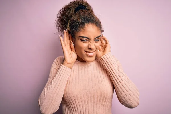 ピンクの背景に立ってカジュアルなセーターを着て若い美しいアフリカ系アメリカ人の女の子耳のジェスチャーで両手を聞くしようとすると ゴシップへの好奇心 聴覚障害 聴覚障害 — ストック写真
