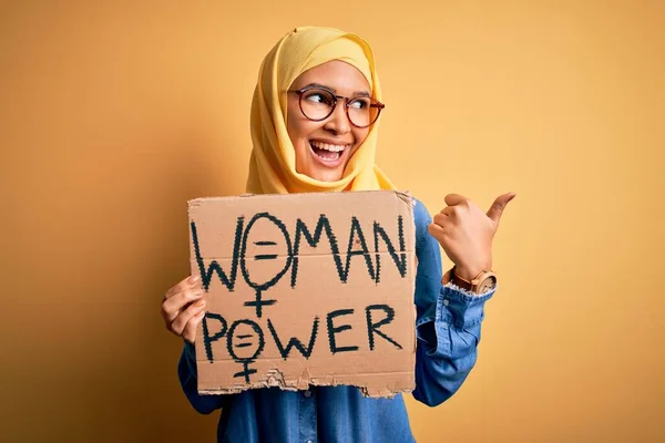 美しいです巻き毛を身に着けているイスラム教徒のヒジャーブは 女性の権利を保持するバナーを指していると幸せな顔の笑顔で親指で側まで表示 — ストック写真