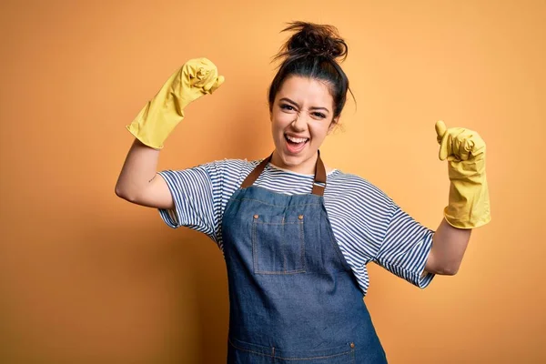 Νεαρή Μελαχρινή Καθαρίστρια Γυναίκα Φορώντας Γάντια Καθαριότητας Πάνω Από Κίτρινο — Φωτογραφία Αρχείου