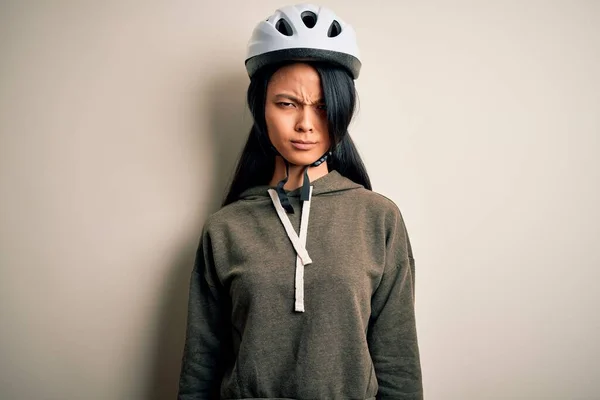 年轻美丽的中国女人戴着自行车头盔 在孤独的白色背景下显得怀疑和紧张 因为问题而皱着眉头 消极的人 — 图库照片