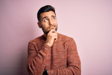 İzole edilmiş pembe arka plan üzerinde duran, soru soran, düşünceli bir genç, yakışıklı adam. Düşünceli bir yüzle gülümsüyor. Şüphe kavramı.