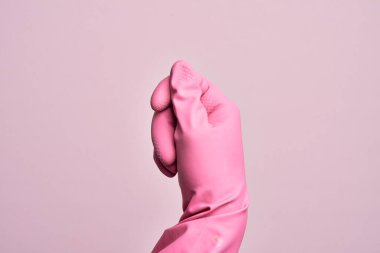 İzole edilmiş pembe arka plan üzerinde temizlik eldiveni olan beyaz bir gencin eli parmak, iş ve reklamla boş bir alan tutuyor.