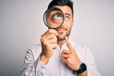 Genç dedektif, izole edilmiş arka planda büyüteçten bakıyor. Ciddi bir yüz. Soru sormayı düşünüyor.