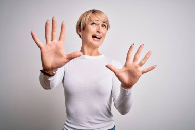 Çağdaş kısa saçlı genç, sarışın bir kadın izole edilmiş arka planda duruyor korku ifadesinden korkuyor ve dehşete kapılmış halde. El hareketlerini durdur, şok içinde bağır. Panik konsepti.