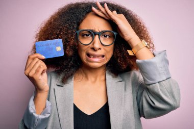 Afro saçlı, pembe arka planda kredi kartı tutan Afro Amerikalı genç bir iş kadını. Kafa kafaya verip, utanç ve şaşkınlık içinde, sinirli ve hayal kırıklığına uğramış bir halde. Hata için korku ve üzüntü.