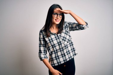 Mavi gözlü genç esmer kadın beyaz arka planda günlük gömlek ve gözlük takıyor çok mutlu ve tebessüm ediyor. Konsept aranıyor.