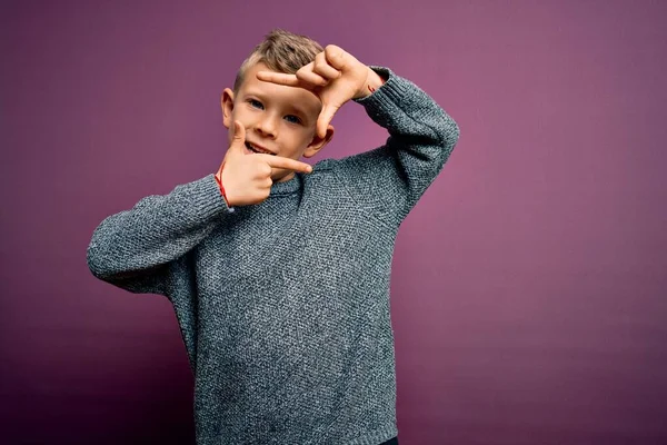 紫色の背景に立って冬のセーターを着て青い目をした若い白人の子供は 幸せな顔をした手と指でフレームを作り笑顔 創造性と写真の概念 — ストック写真