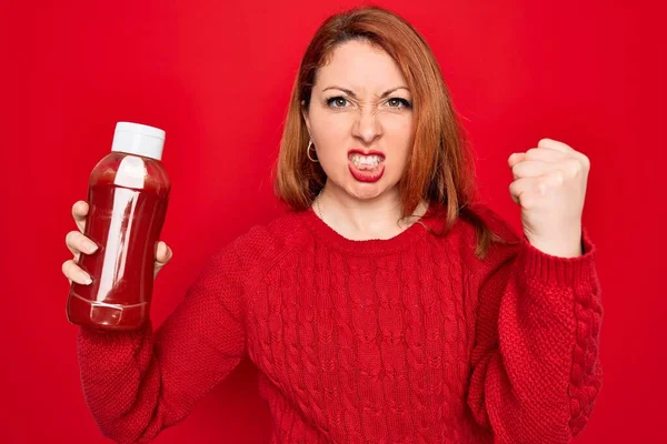 Schöne Rothaarige Frau Mit Einer Flasche Ketchupflasche Über Rotem Hintergrund — Stockfoto
