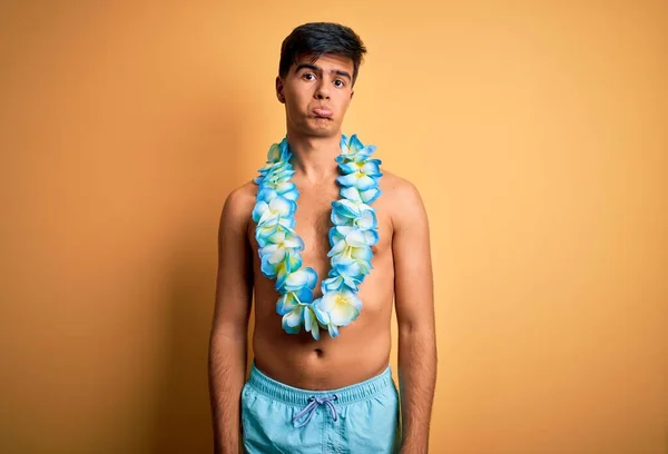 休暇中の若いハンサムな観光客の男性は水着とハワイのレイの花を着て落ち込んで苦痛を心配し 怒っていると恐れて泣いている 悲しい表情 — ストック写真