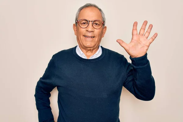 Senior handsome grey-haired man wearing sweater and glasses over isolated white background showing and pointing up with fingers number five while smiling confident and happy.