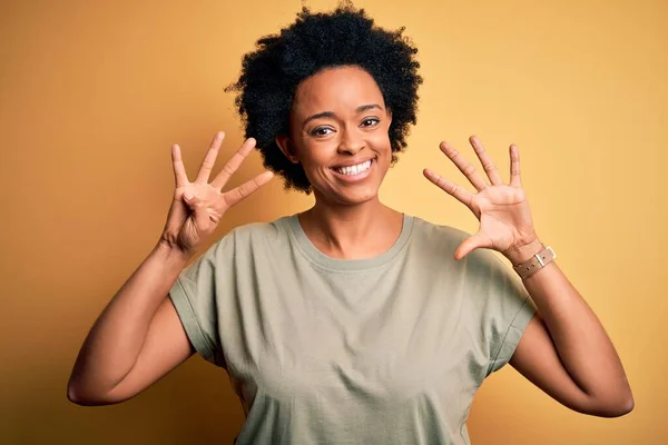 若いです美しいですアフリカ系アメリカ人アフロ女性とともに巻き毛を身に着けていますカジュアルTシャツショーと指番号9で指摘しながら 自信と幸せ — ストック写真