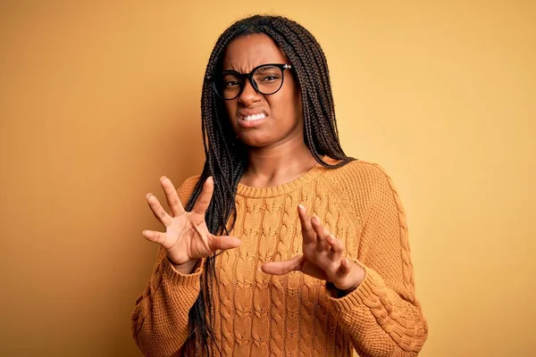 年轻的非洲聪明女人 戴着眼镜 身穿休闲衫 背景黄色 表情令人讨厌 因为厌恶的反应而不高兴和害怕做厌恶的表情 举手表决 — 图库照片