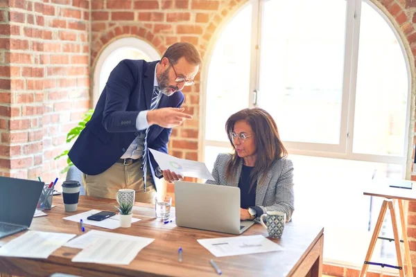 Two middle age business workers working together. Man bullying woman at the office