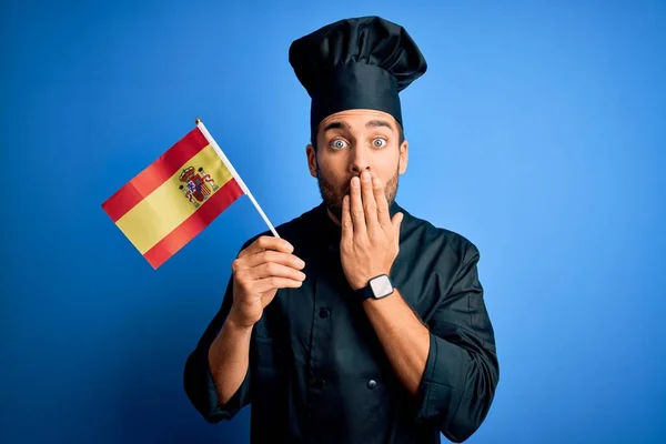 ひげを生やした若いハンサムな炊飯器の男が制服を着てスペインの国旗を手で口をカバーミス 恐怖の表現 沈黙の中で怖がって 秘密の概念 — ストック写真