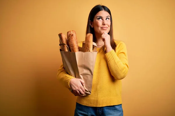 Młoda Piękna Kobieta Trzymając Worek Świeżego Zdrowego Chleba Żółtym Tle — Zdjęcie stockowe