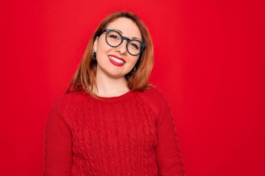 Genç, güzel, kızıl saçlı bir kadın. Kırmızı arka planda gözlüklü, sıradan bir süveter giyiyor. Mutlu ve havalı bir gülümsemesi var. Şanslı kişi..