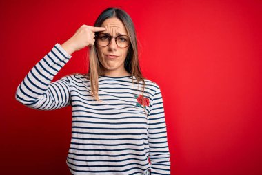 Kırmızı arka planda duran mavi gözlü güzel sarışın kadın alnındaki sivilceden mutsuz olduğunu gösteriyor. Siyah noktalı çirkin bir enfeksiyon. Sivilce ve deri problemi