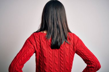 Mavi gözlü genç esmer kadın izole edilmiş beyaz arka planda günlük süveter giyiyor geriye doğru bakıyor kolları vücudunda.