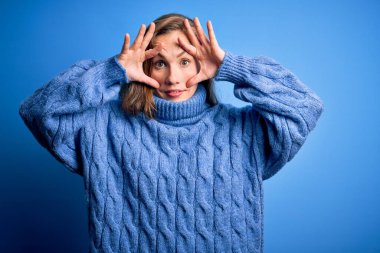 Mavi arka planda balıkçı yaka kazak giyen genç, güzel sarışın kadın gözlerini parmaklarıyla açmaya çalışıyor, uykulu ve yorgunluktan yorgun.