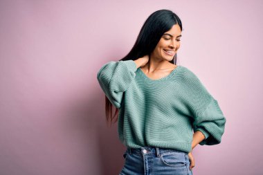 Moda kıyafetleri giyen genç ve güzel bir kadın. Manken, sokak tarzı giyiniyor. Pembe arka planda dikiliyor.