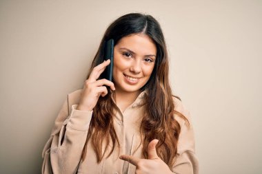 Genç, güzel, esmer bir kadın akıllı telefondan konuşuyor. Şaşırmış bir yüz ifadesiyle kendini işaret ediyor.