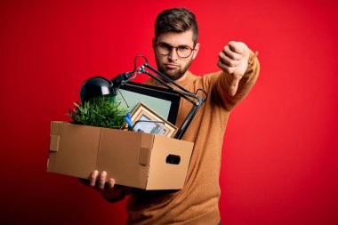 Sarışın, sakallı ve mavi gözlü genç adam elinde kızgın yüzlü karton bir kutu tutarak kovuldu. Negatif işaretler baş parmakları aşağıda, reddedilme kavramından hoşlanmadığını gösteriyor.